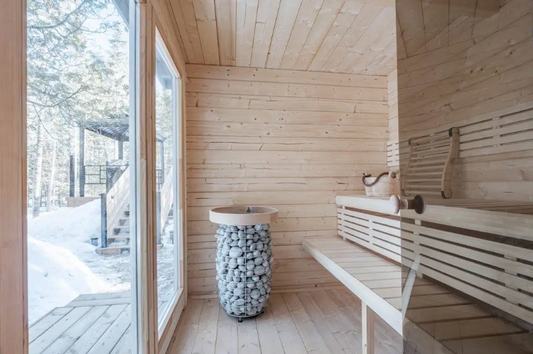 Banc et seau de pierres dans une salle de sauna.