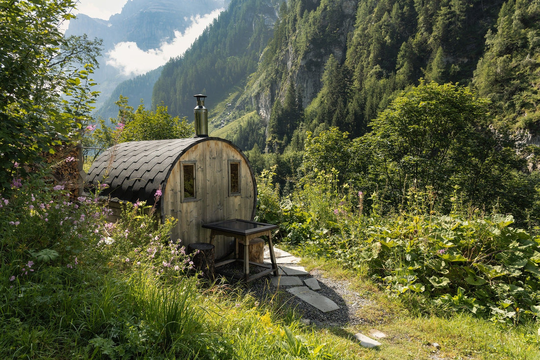 Petit sauna en bois dans une forêt avec table extérieure.