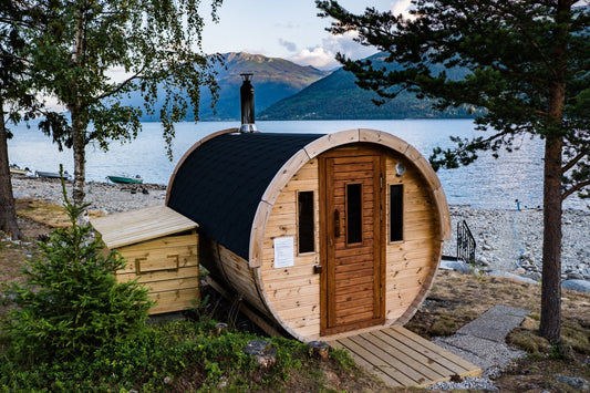 Sauna en tonneau à toit noir au bord d'un lac.