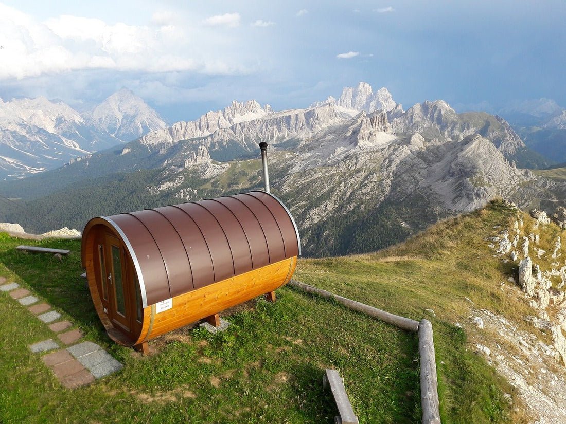 Sauna en tonneau sur une colline avec les montagnes en arrière-plan.