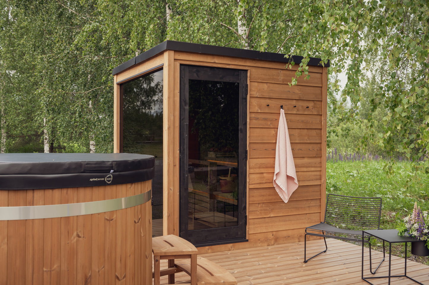 Sauna extérieur Nordic Dawn avec porte en verre et bancs en bois.