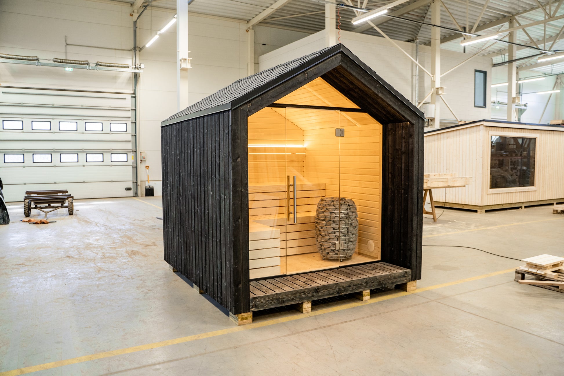 Sauna LUMI avec porte en verre et poêle électrique.