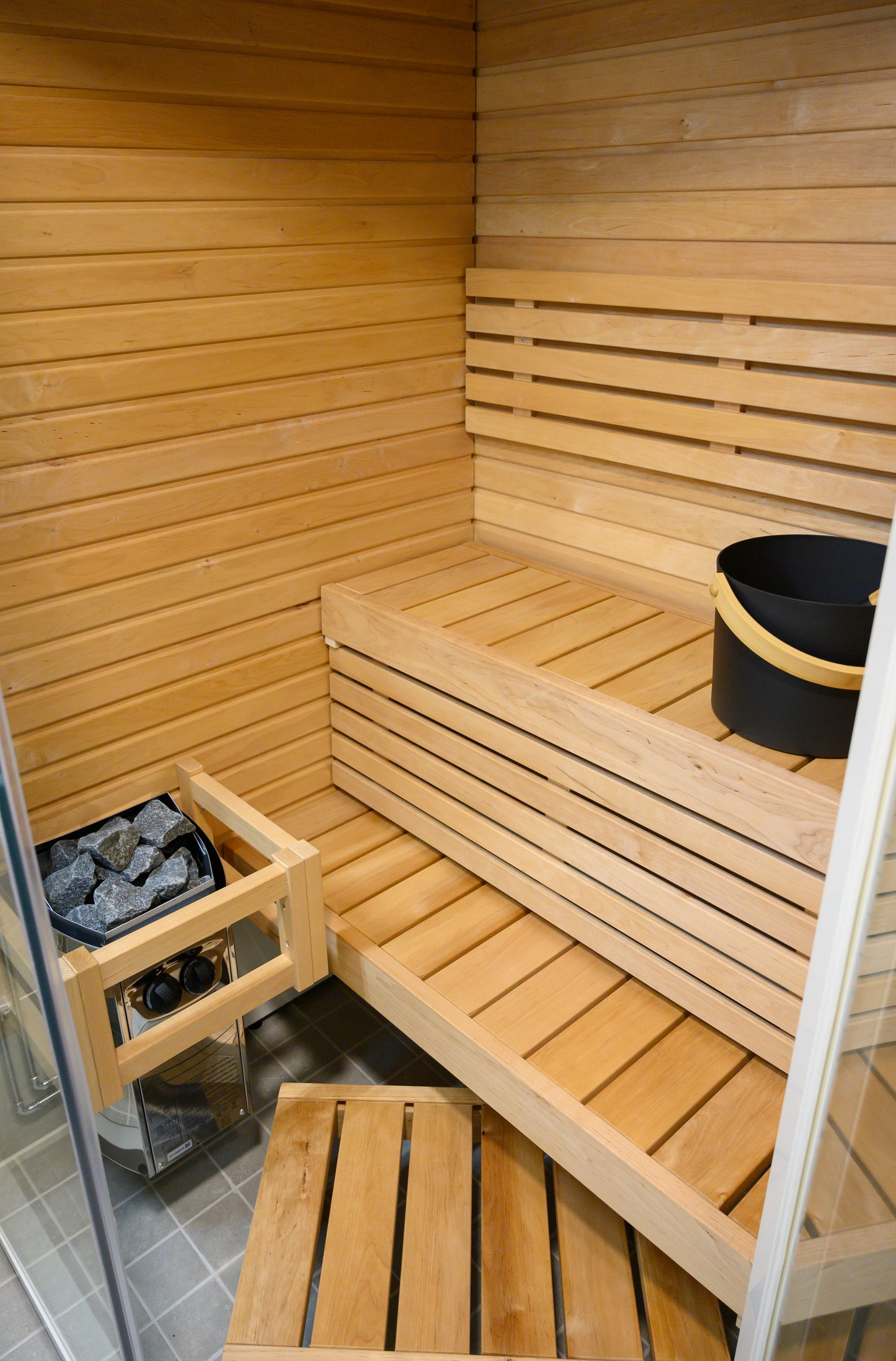 Sauna Sirius Corner avec seau et pierres.