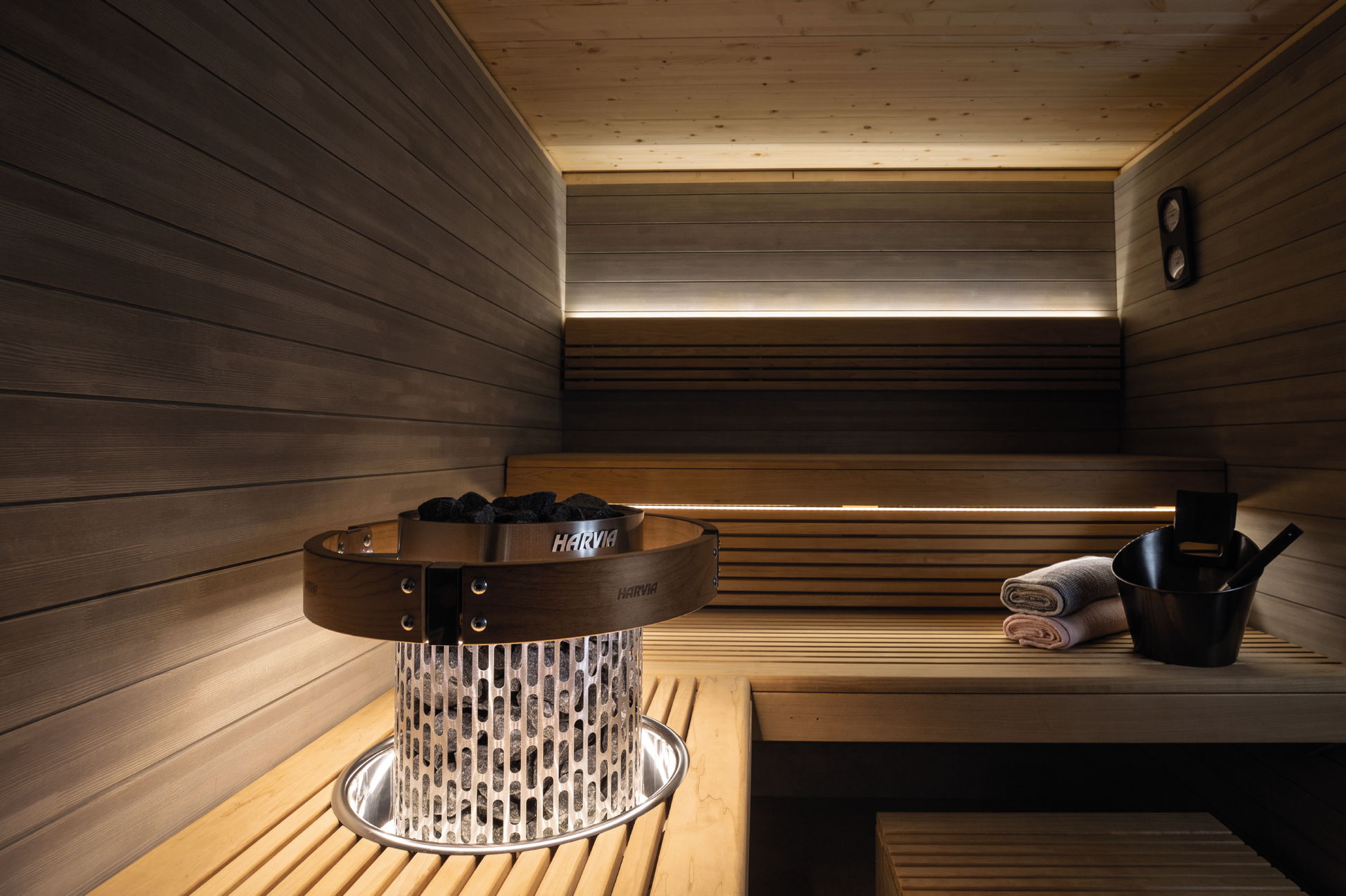 Ensemble d'éclairage LED Harvia dans un sauna avec pierres et seau.