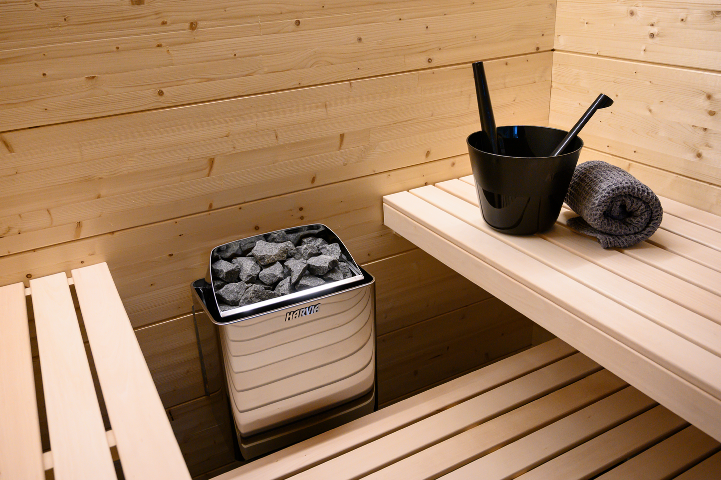 Poêle électrique Harvia KIP dans un sauna avec seau en pierre.