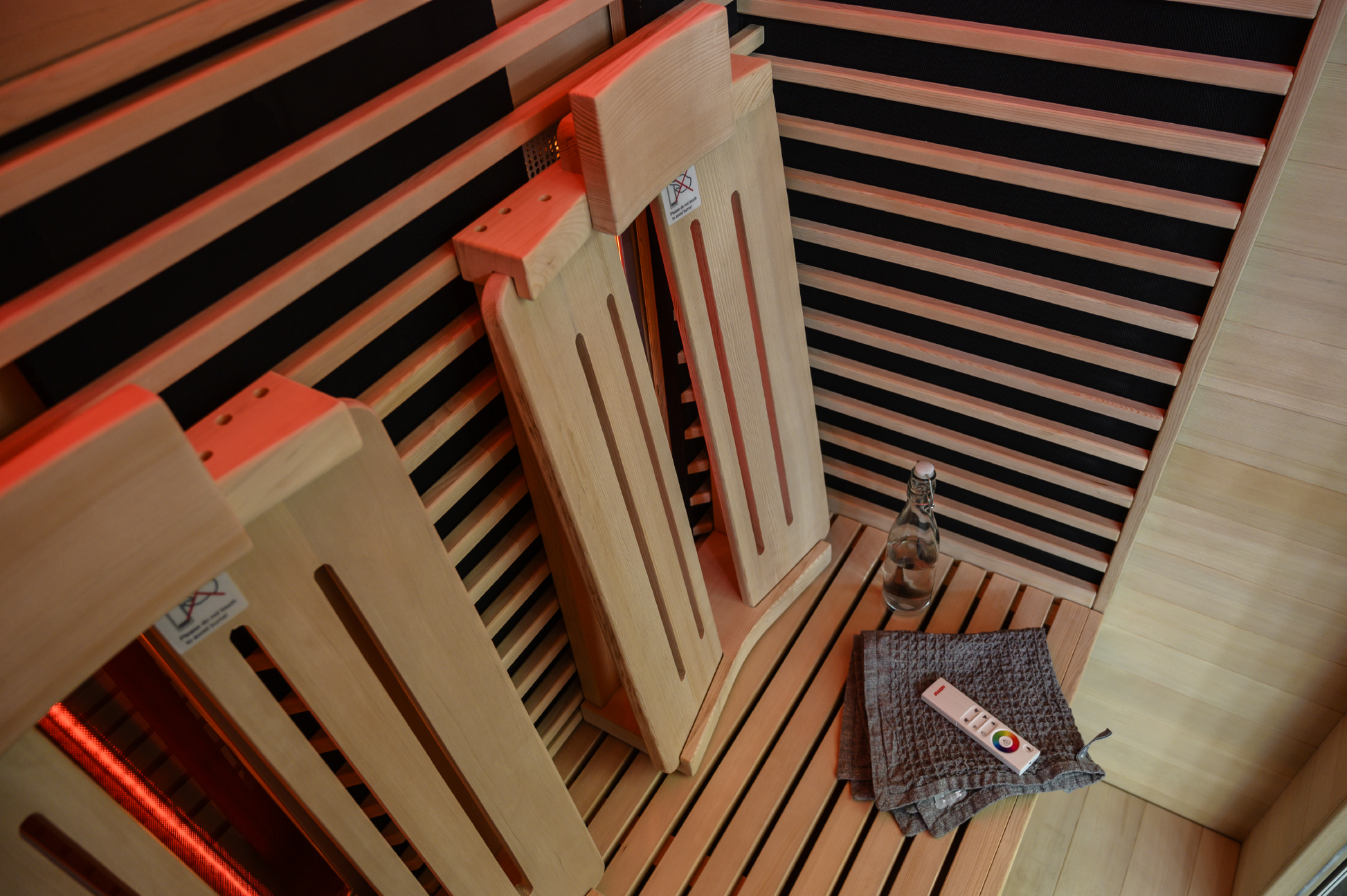 Sauna infrarouge à spectre avec chaises en bois et télécommande.