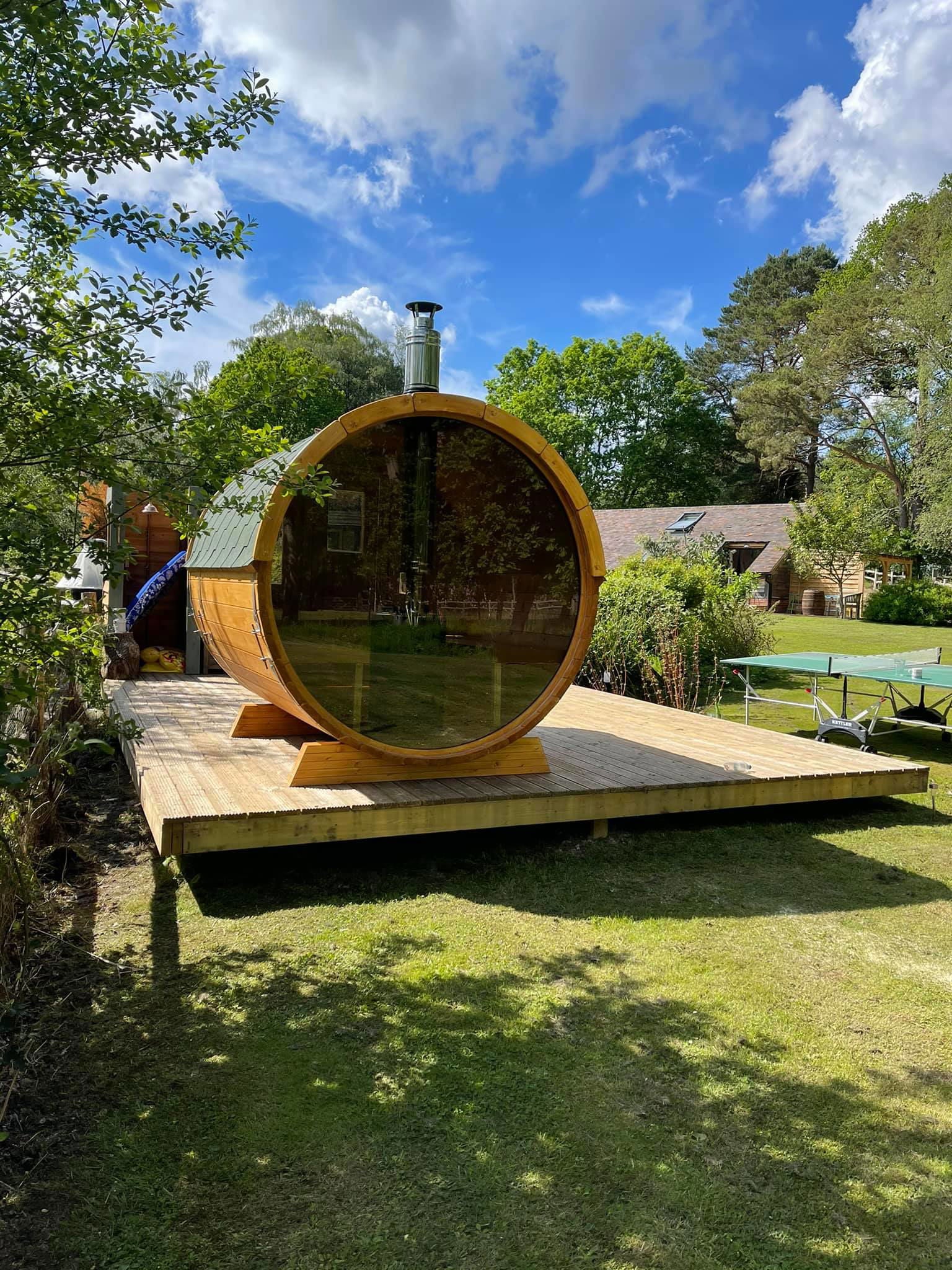 Saunamo Sauna extérieur Barrel 250 avec paroi en verre sur une terrasse en bois.