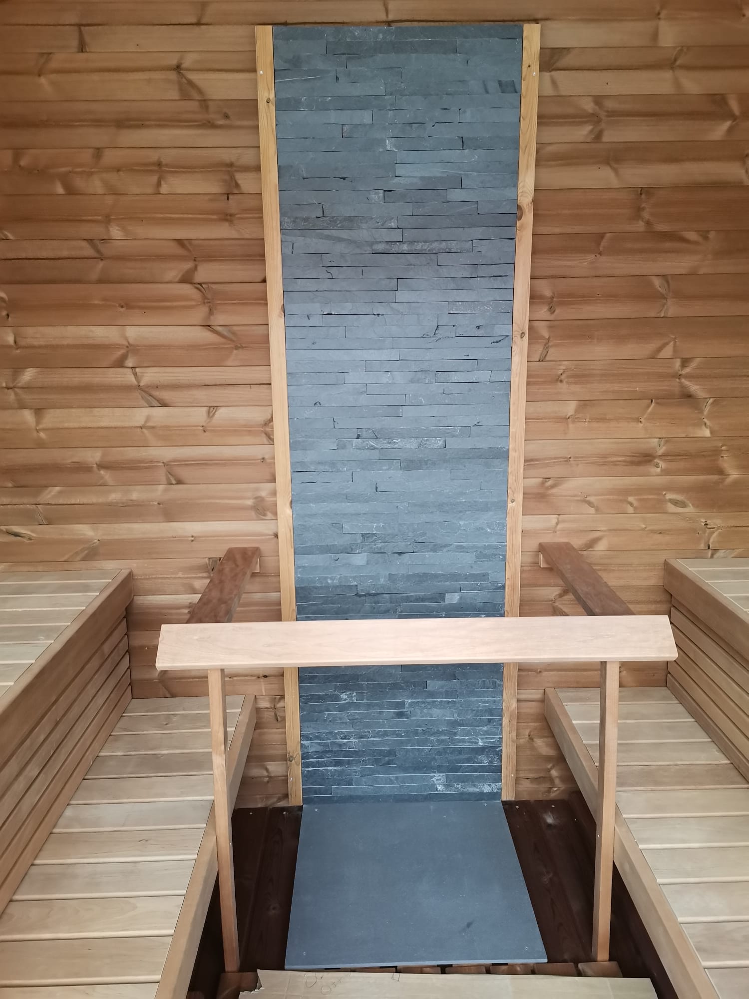 Saunamo Sauna Cubus avec mur en pierre et bancs en bois.