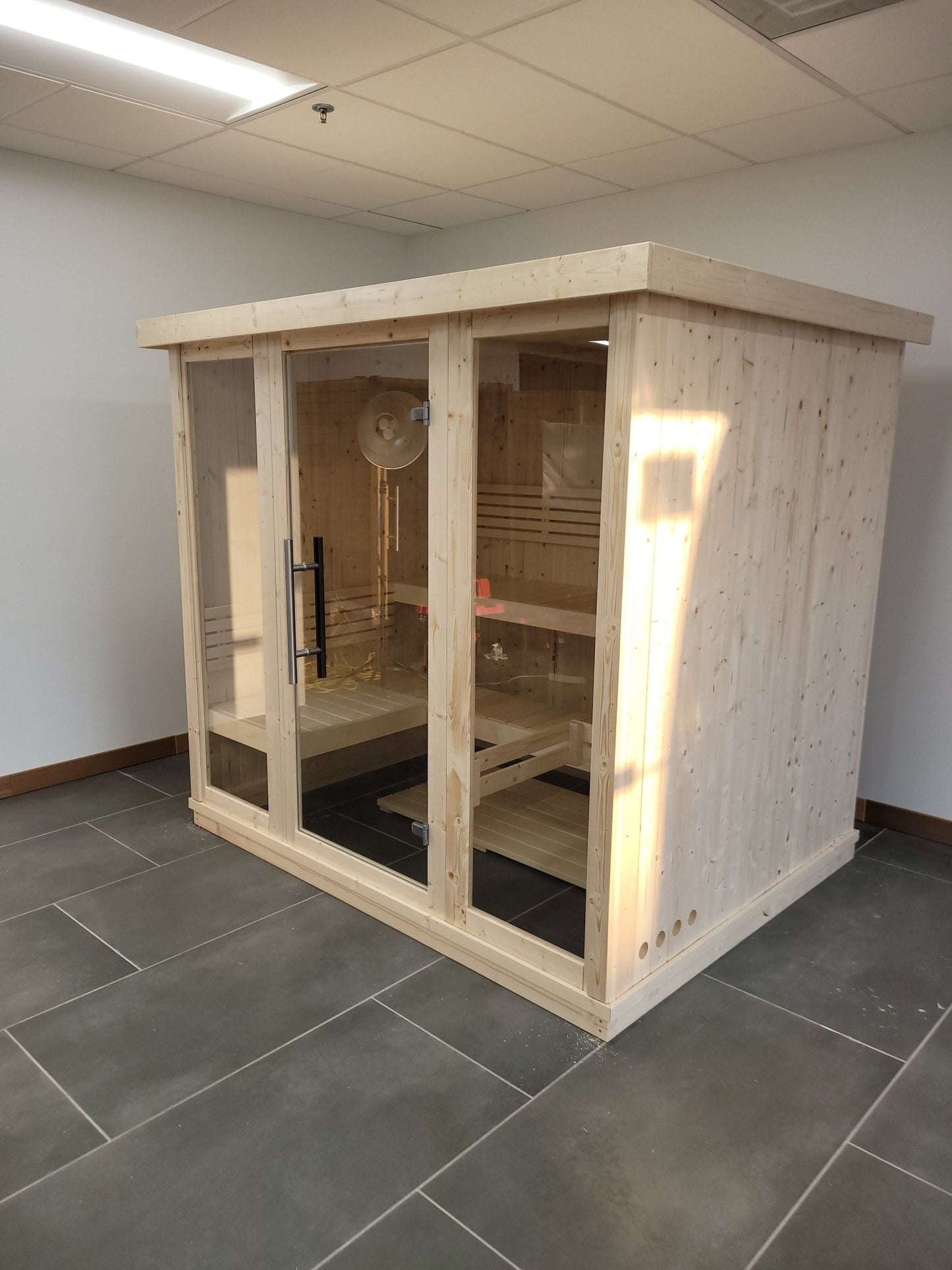 Grand sauna intérieur avec portes en verre trempé.