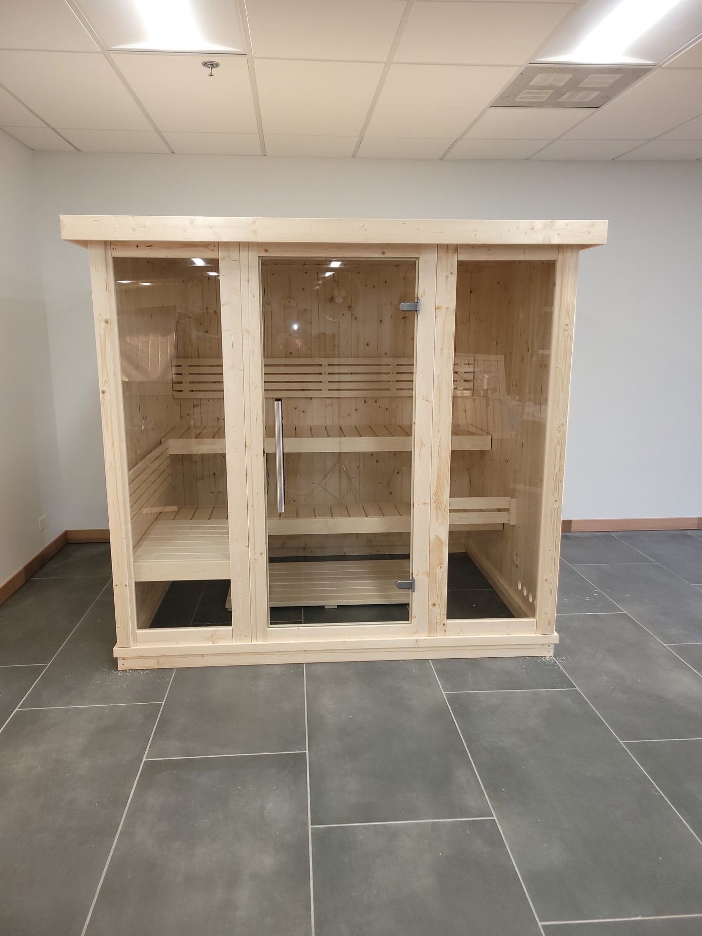 Grand sauna intérieur en bois avec portes en verre trempé.