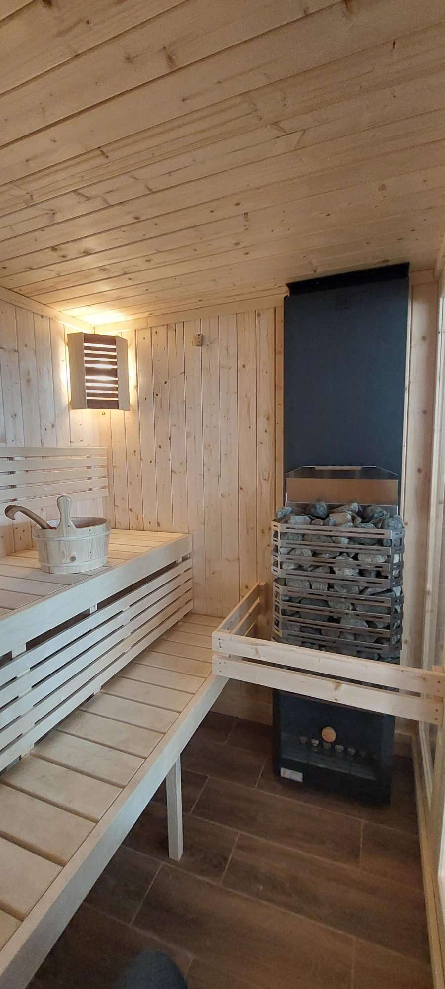 Grand sauna intérieur avec seau et pierres.