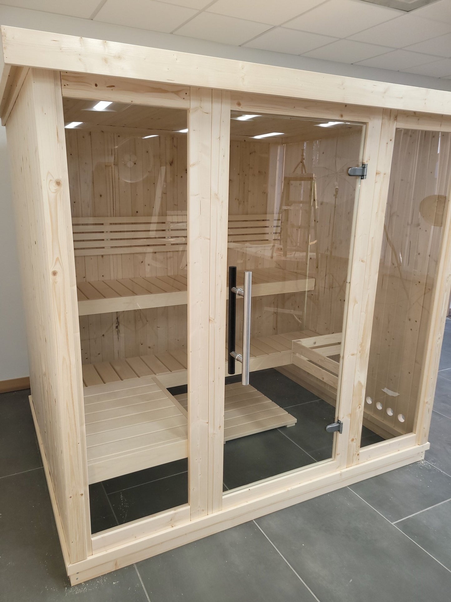 Grand sauna intérieur en bois avec portes en verre.