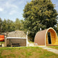 Saunamo Pod à côté d'une cabane en bois et d'un jardin.